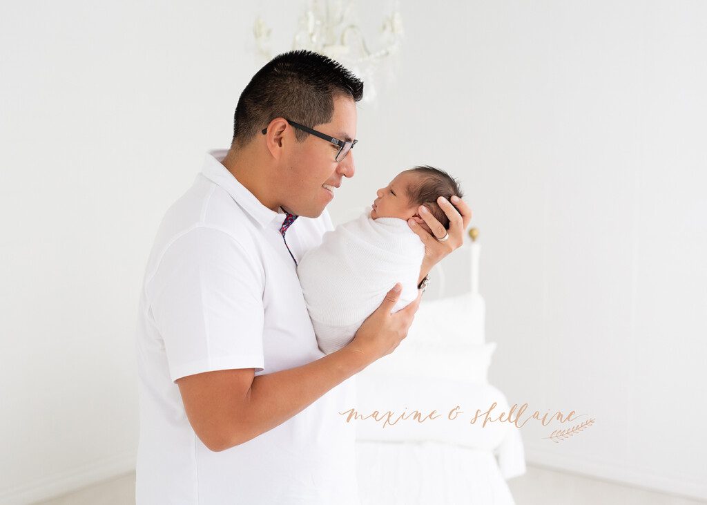 alt=high key image of dad and baby, alt=dad with newborn on light background