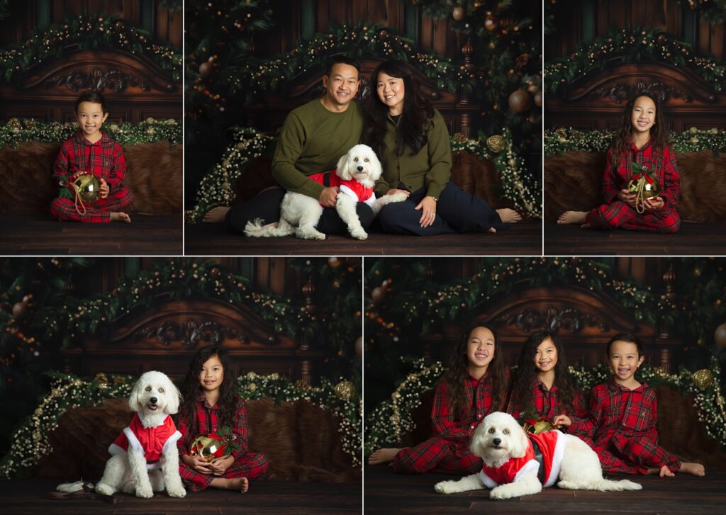 alt=Three children in matching red plaid pajamas sitting barefoot on a Christmas bed set, with dog, laughing together with greenery, lights, and warm wooden holiday décor behind them